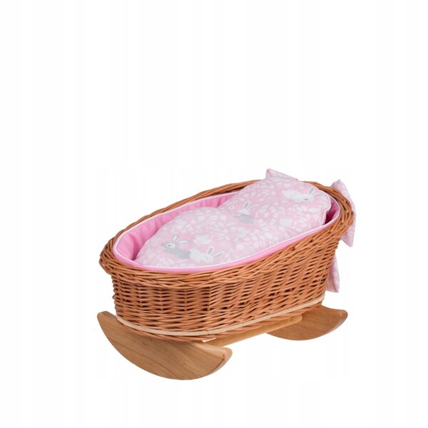 Ein Puppenbett aus Korbgeflecht mit rosafarbenen Paspeln, einem Kissen und einer Steppdecke