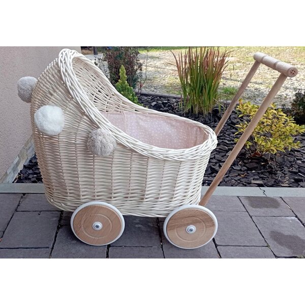 Ecrufarbener Puppenwagen aus Korbgeflecht mit Bettwäsche und Pompons – ein umweltfreundliches Spielzeug
