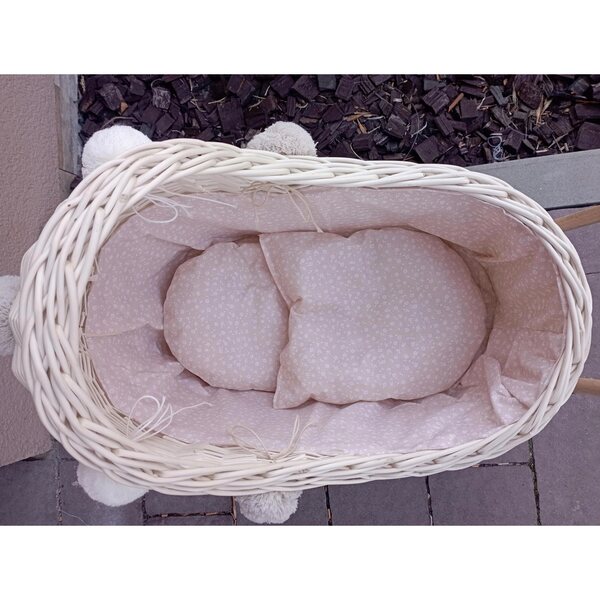 Ecrufarbener Puppenwagen aus Korbgeflecht mit Bettwäsche und Pompons – ein umweltfreundliches Spielzeug