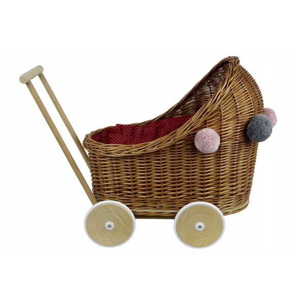 Ein tiefer Puppenwagen aus Korbgeflecht mit Bettwäsche und Pompons für Babys ab 12 Monaten