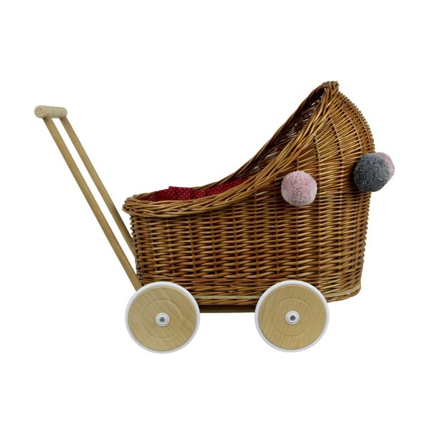 Ein tiefer Puppenwagen aus Korbgeflecht mit Bettwäsche und Pompons für Babys ab 12 Monaten