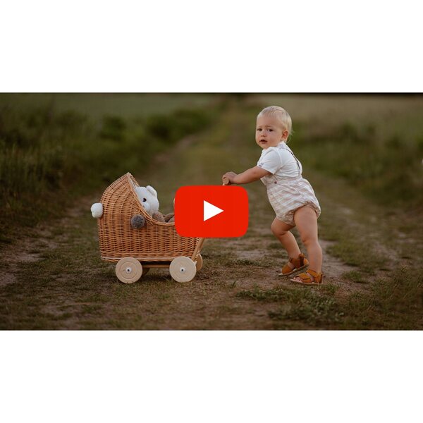 Niedriger Puppenwagen aus Naturgeflecht mit Pompons und rosa Verzierung
