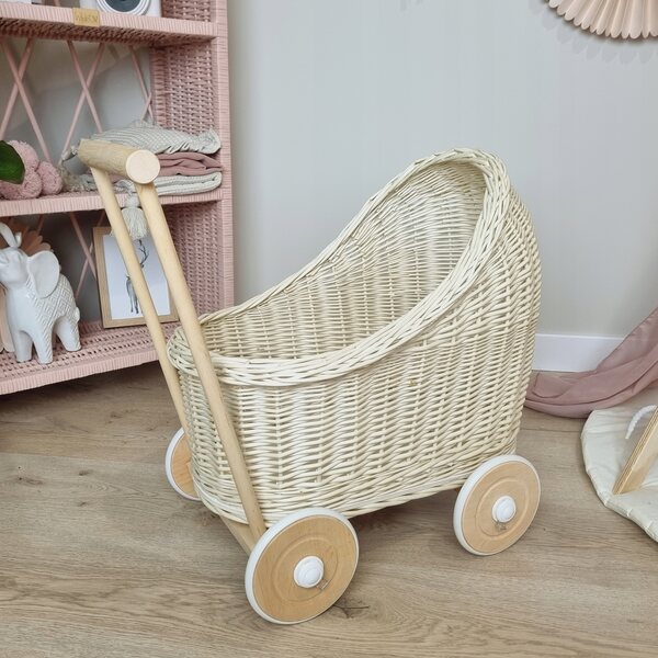 Ein ecrufarbener Korbwagen für Puppen mit Baumwollbettwäsche und Holzrädern