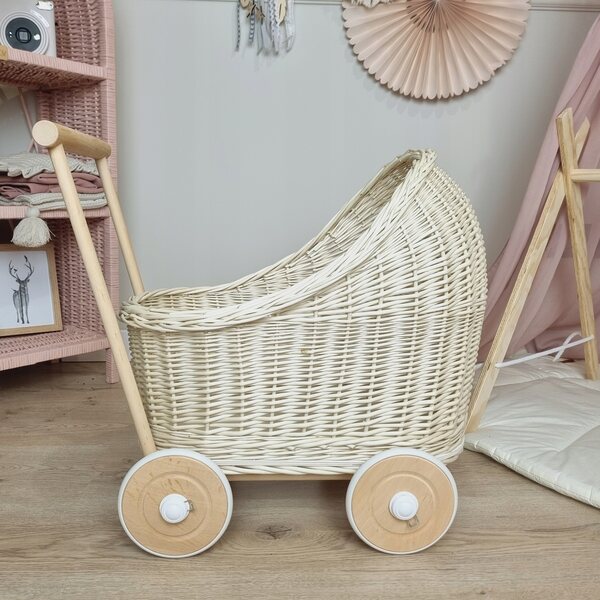 Ein ecrufarbener Korbwagen für Puppen mit Baumwollbettwäsche und Holzrädern