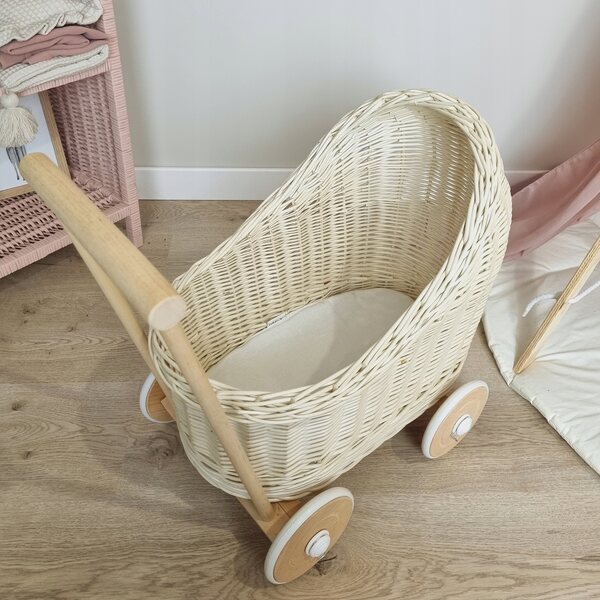 Ein ecrufarbener Korbwagen für Puppen mit Baumwollbettwäsche und Holzrädern